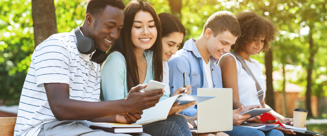 Students on a university campus sit outside and study together. Universities are a key growth markets focus for LifeSpeak.