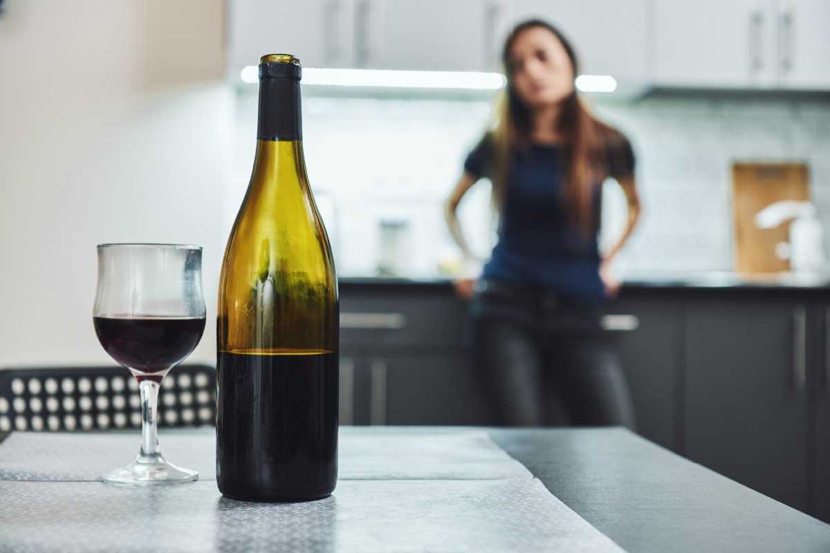A woman stares at a glass of red wine, trying to manage her addiction.
