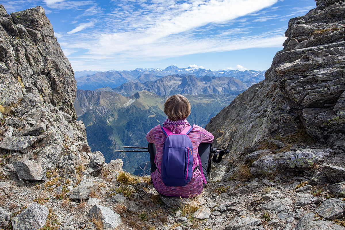A female employee sits an top of a mountain enjoying the view after building resilience during the climb.